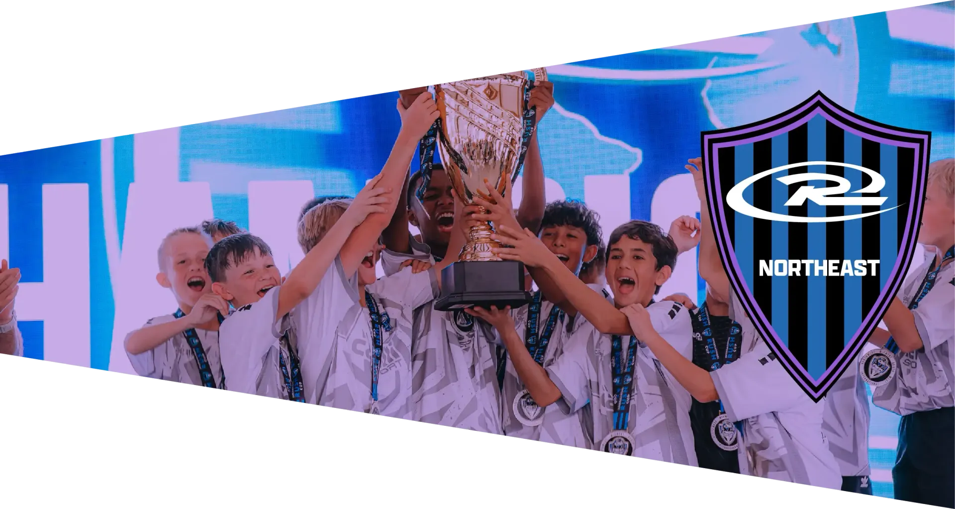 Soccer team celebrates victory on a field, holding a banner; logo in the corner.