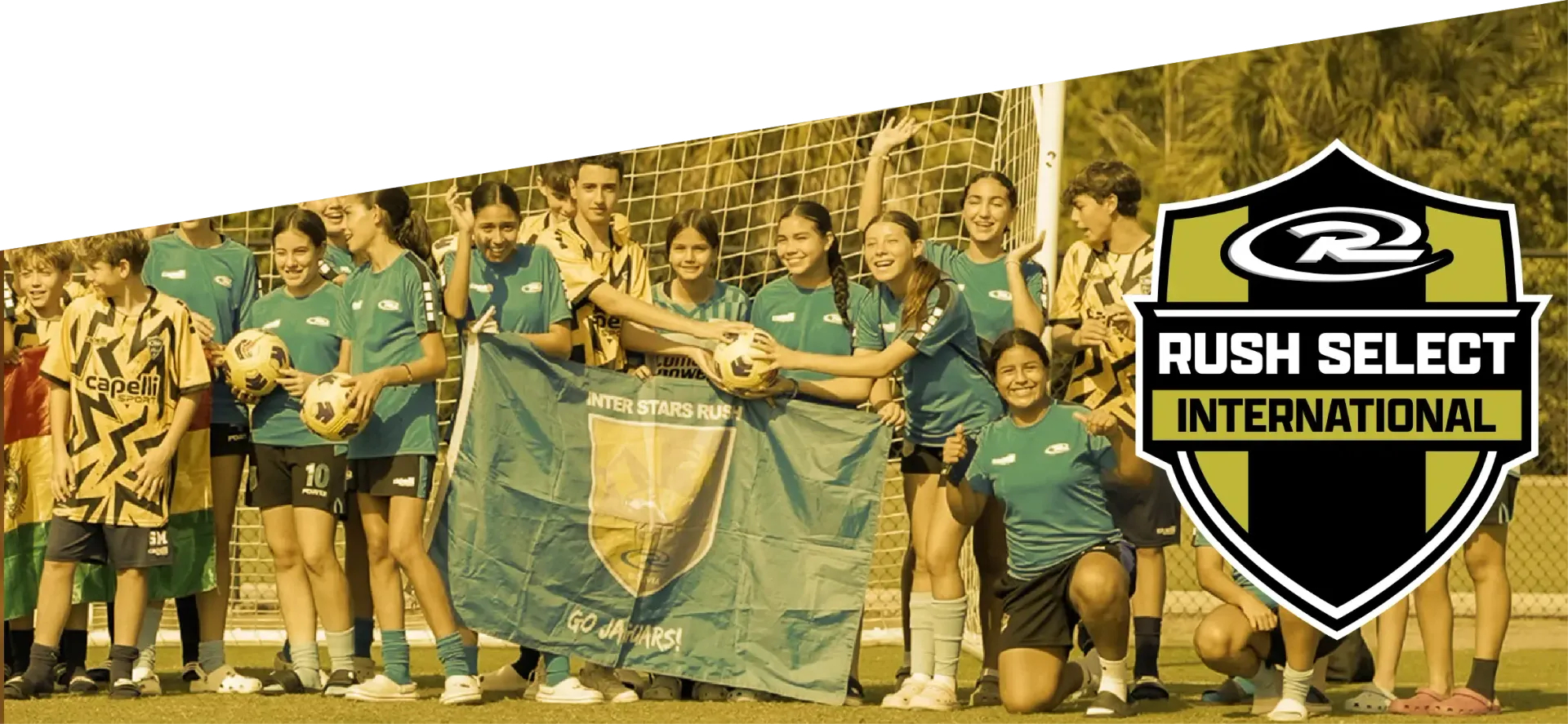 Group of smiling girls in blue soccer jerseys, with team logo, possibly soccer team photo.