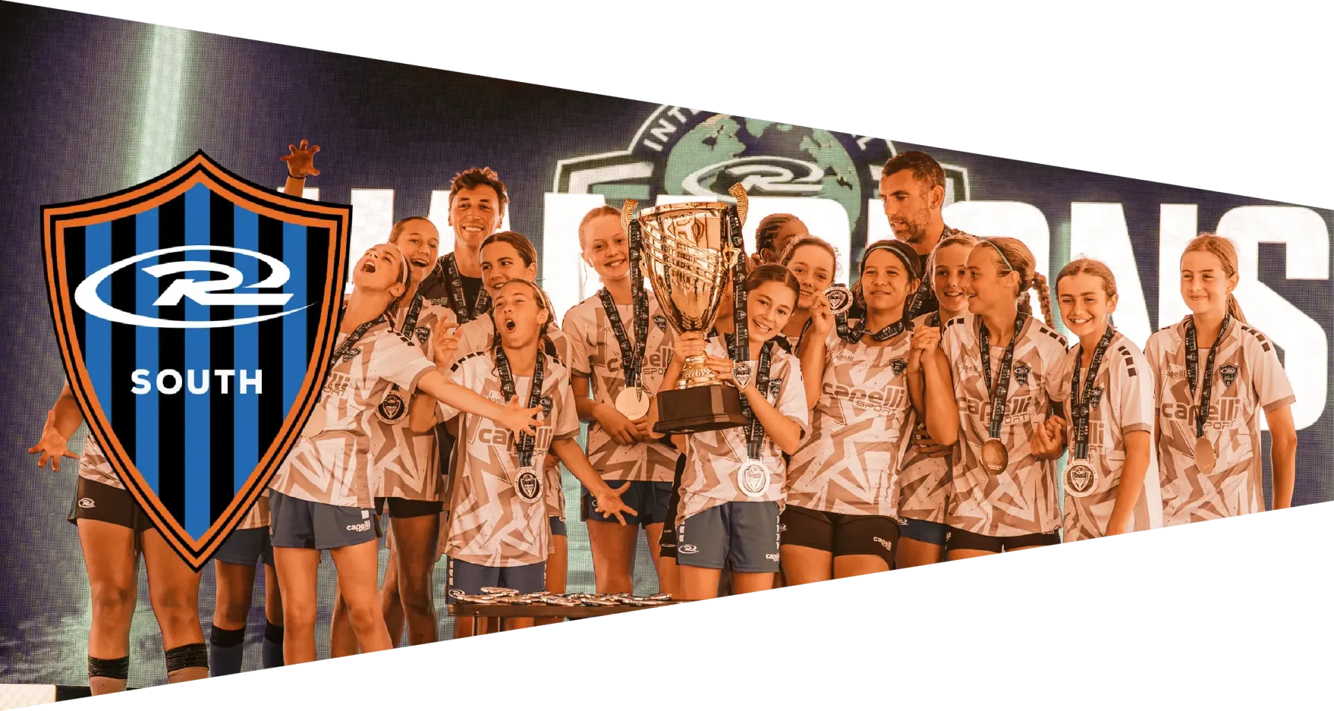 Cheer team holding trophies, wearing matching shirts, celebrating on a stage with a banner reading