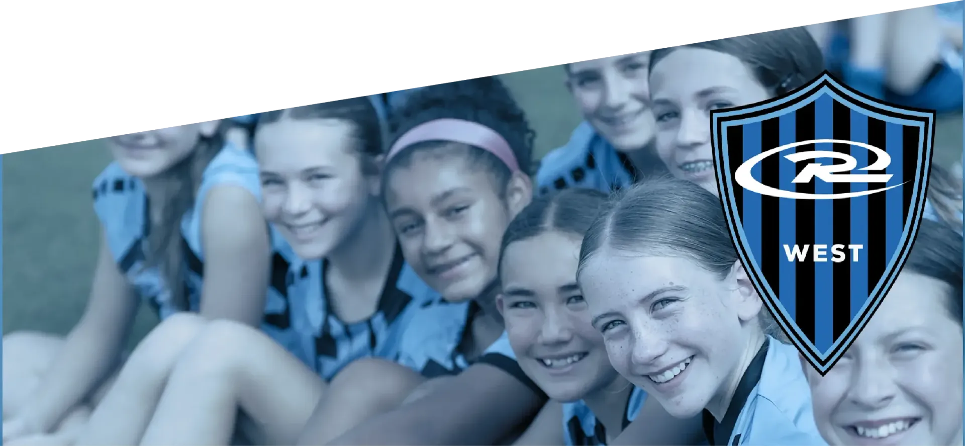 Group of smiling girls in blue soccer jerseys, with team logo, possibly soccer team photo.