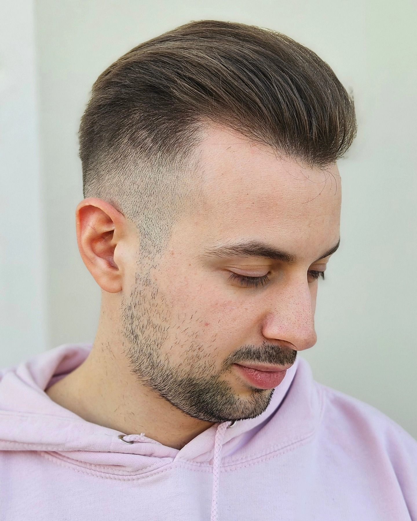 Un uomo con la barba indossa una felpa rosa con cappuccio.