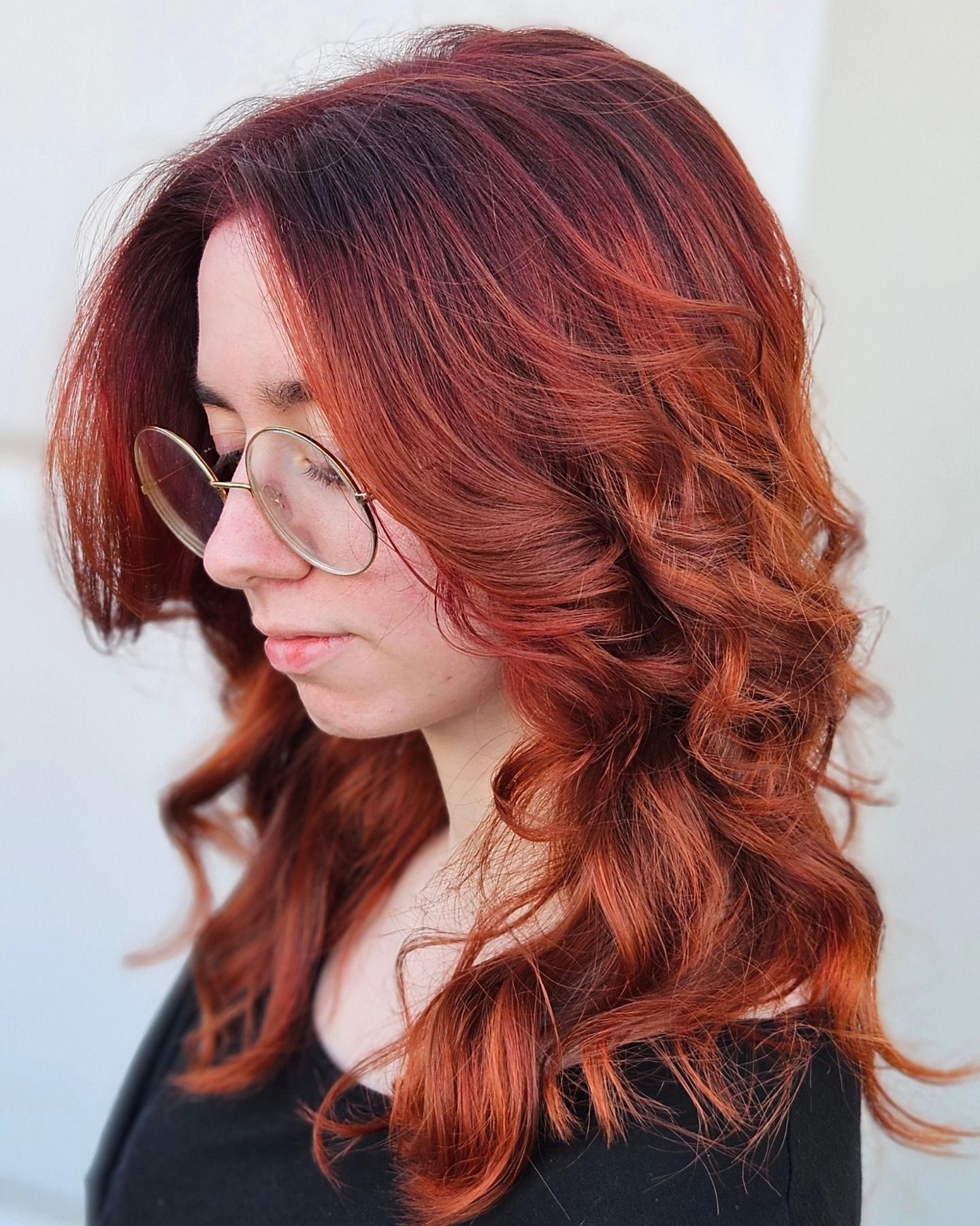 Una donna con i capelli rossi e gli occhiali indossa una maglietta nera.