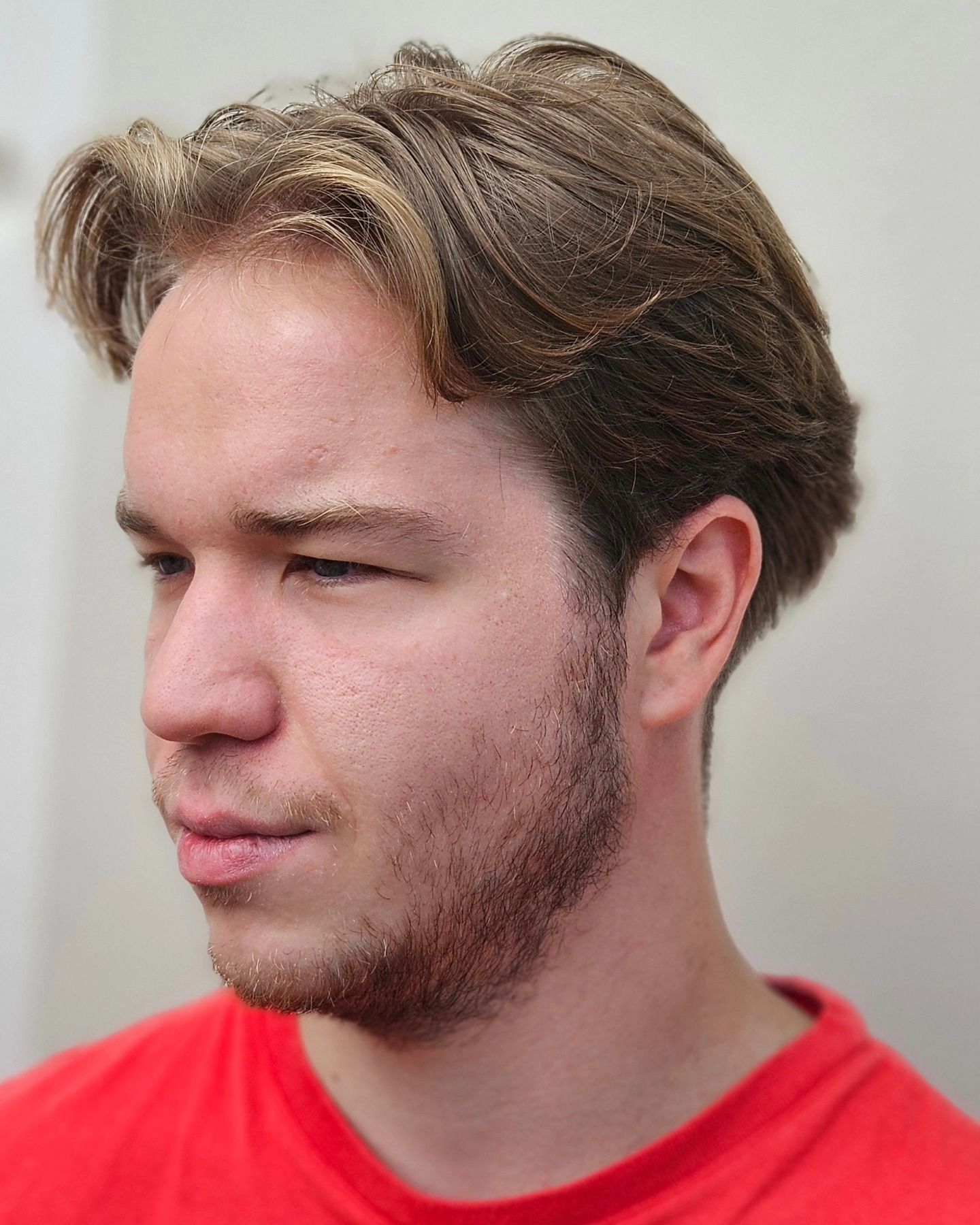 Un uomo con la barba indossa una camicia rossa