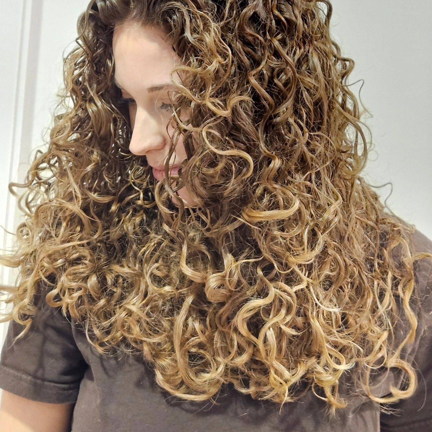 Una donna con lunghi capelli ricci indossa una camicia marrone