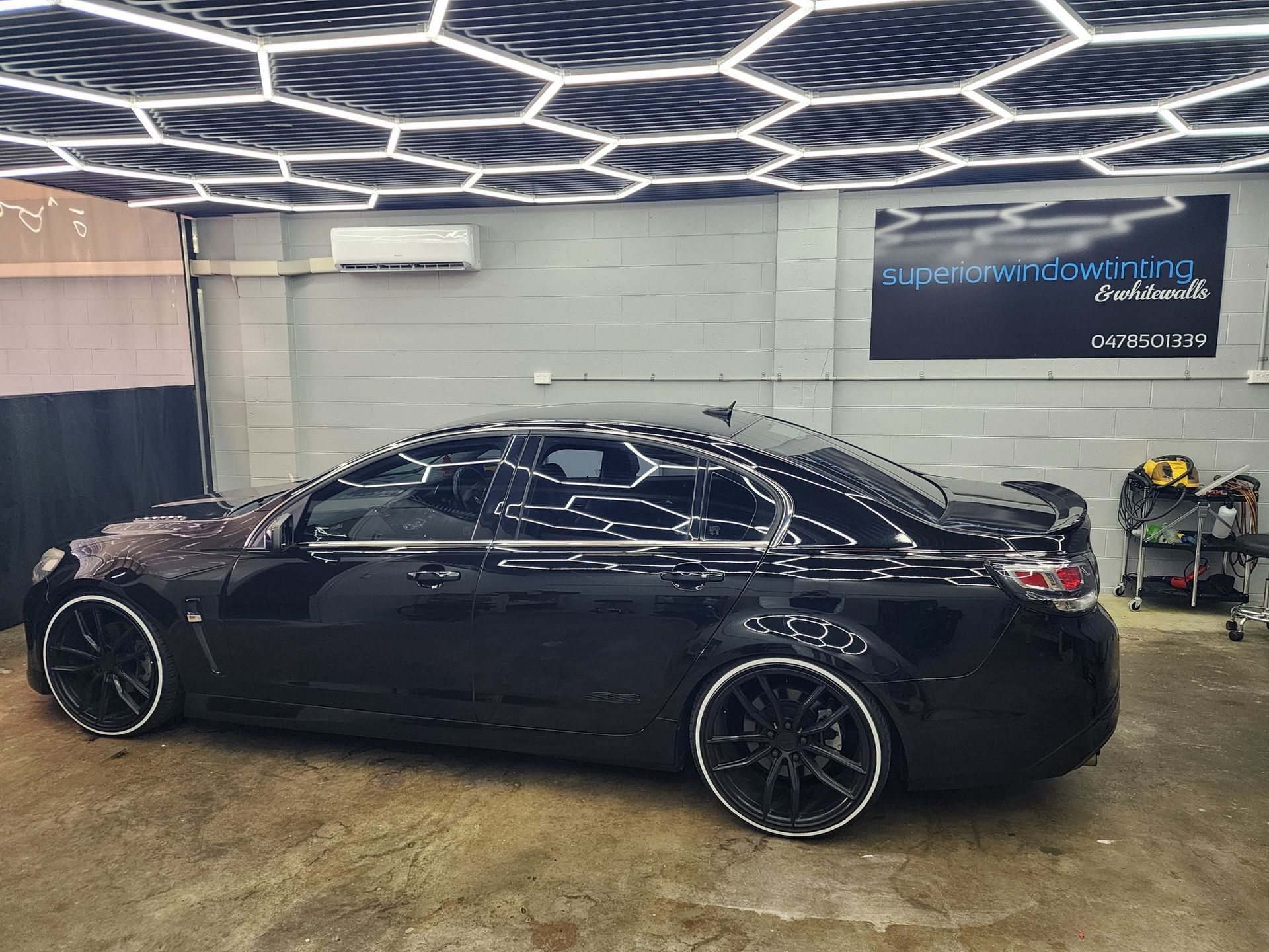 A Glossy Black Sedan Parked in a Garage — Superior Window Tinting & Whitewalls in Portsmith, QLD