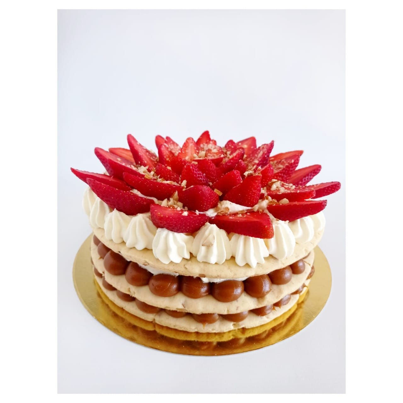 Pastel de fresas y dulce de leche con capas de crema y cubierto con fresas en rodajas.