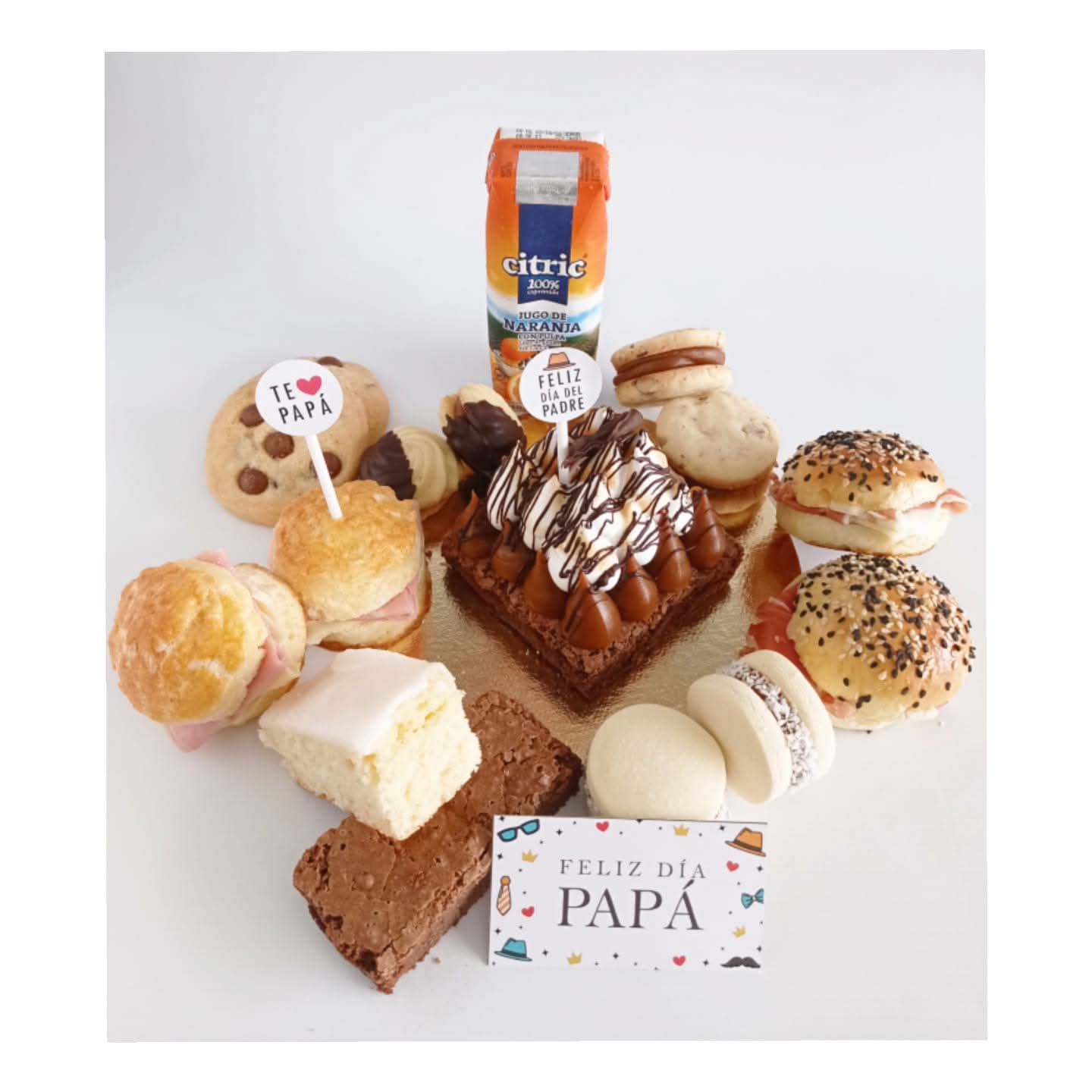 Una canasta de desayuno o merienda con pasteles, jugo y una tarjeta de 