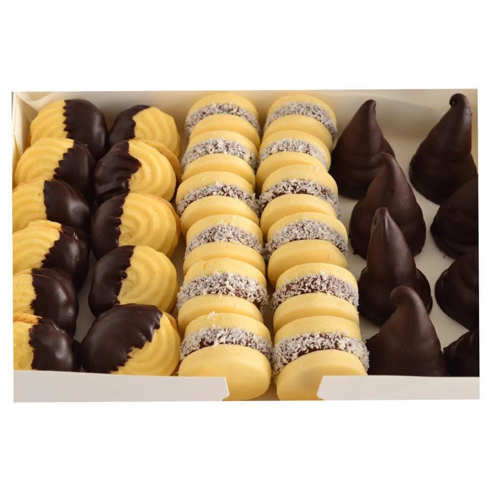 Una caja de galletas surtidas: galletas tipo sándwich bañadas en chocolate, cubiertas con coco y pasteles cónicos.