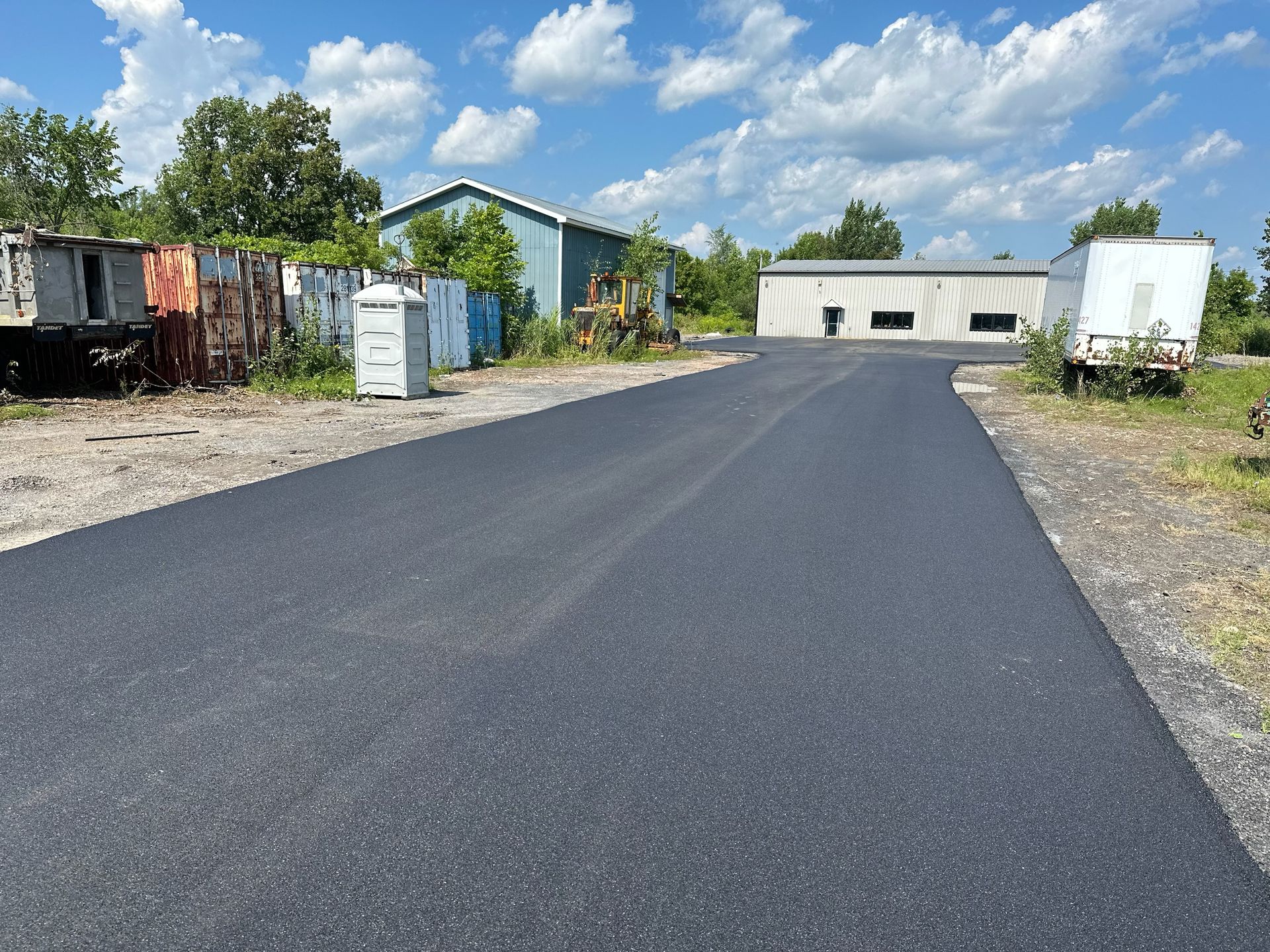 A newly paved road with a building in the background