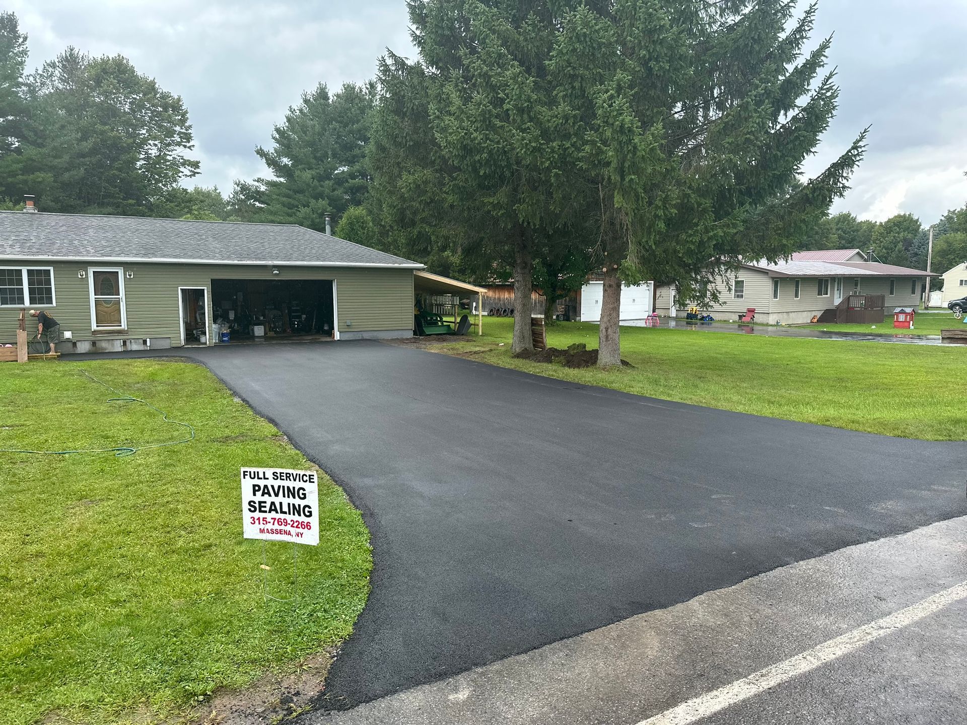 A house with a paved driveway and a sign in front of it.