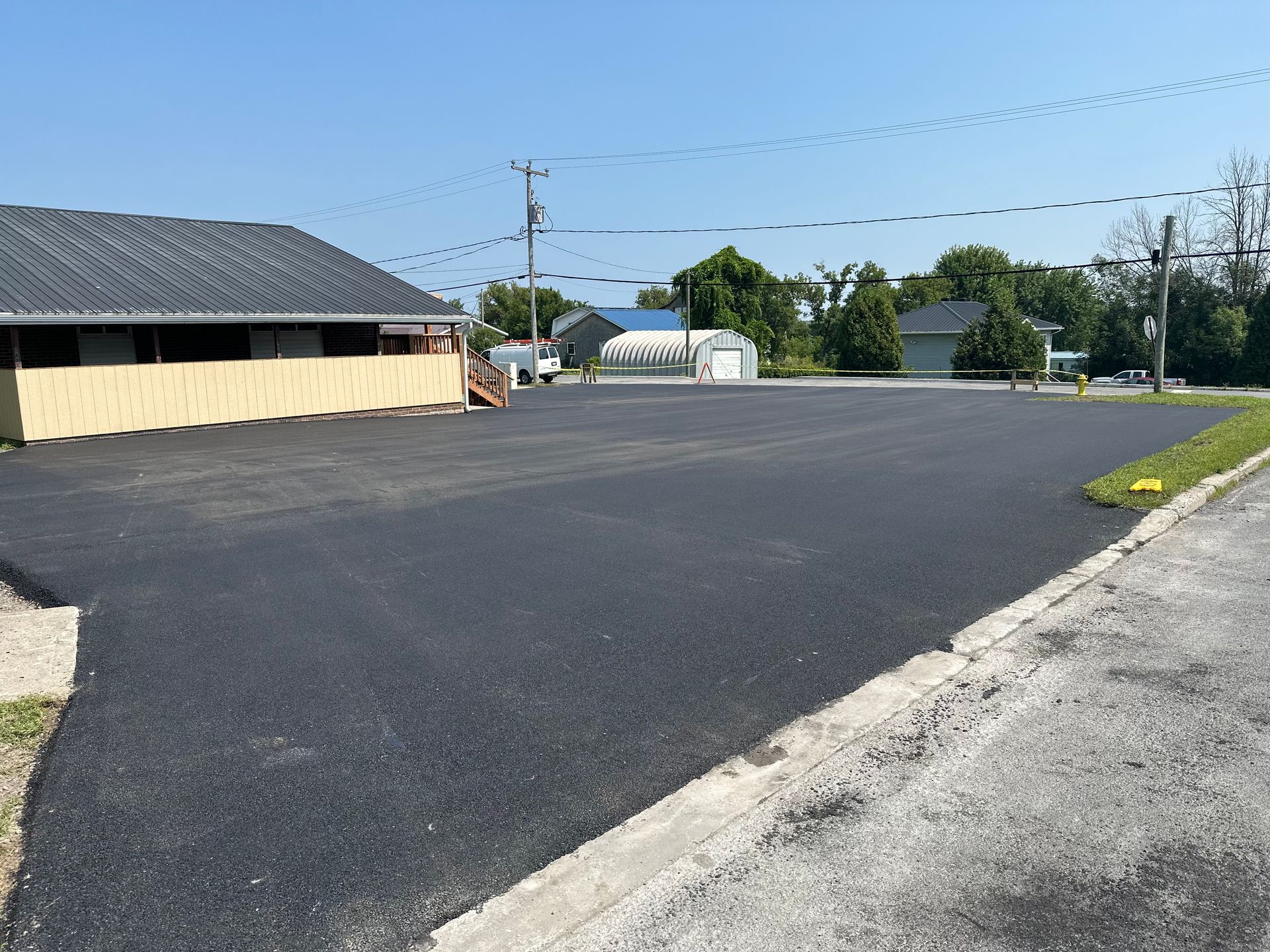 A large asphalt parking lot with a house in the background.