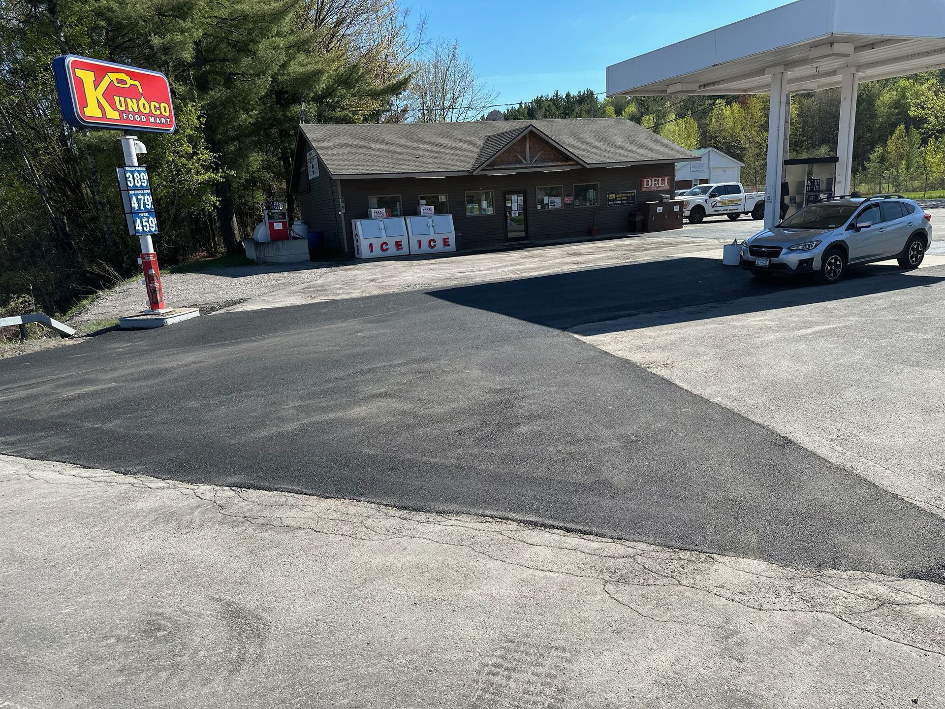 A white car is parked in front of a gas station.