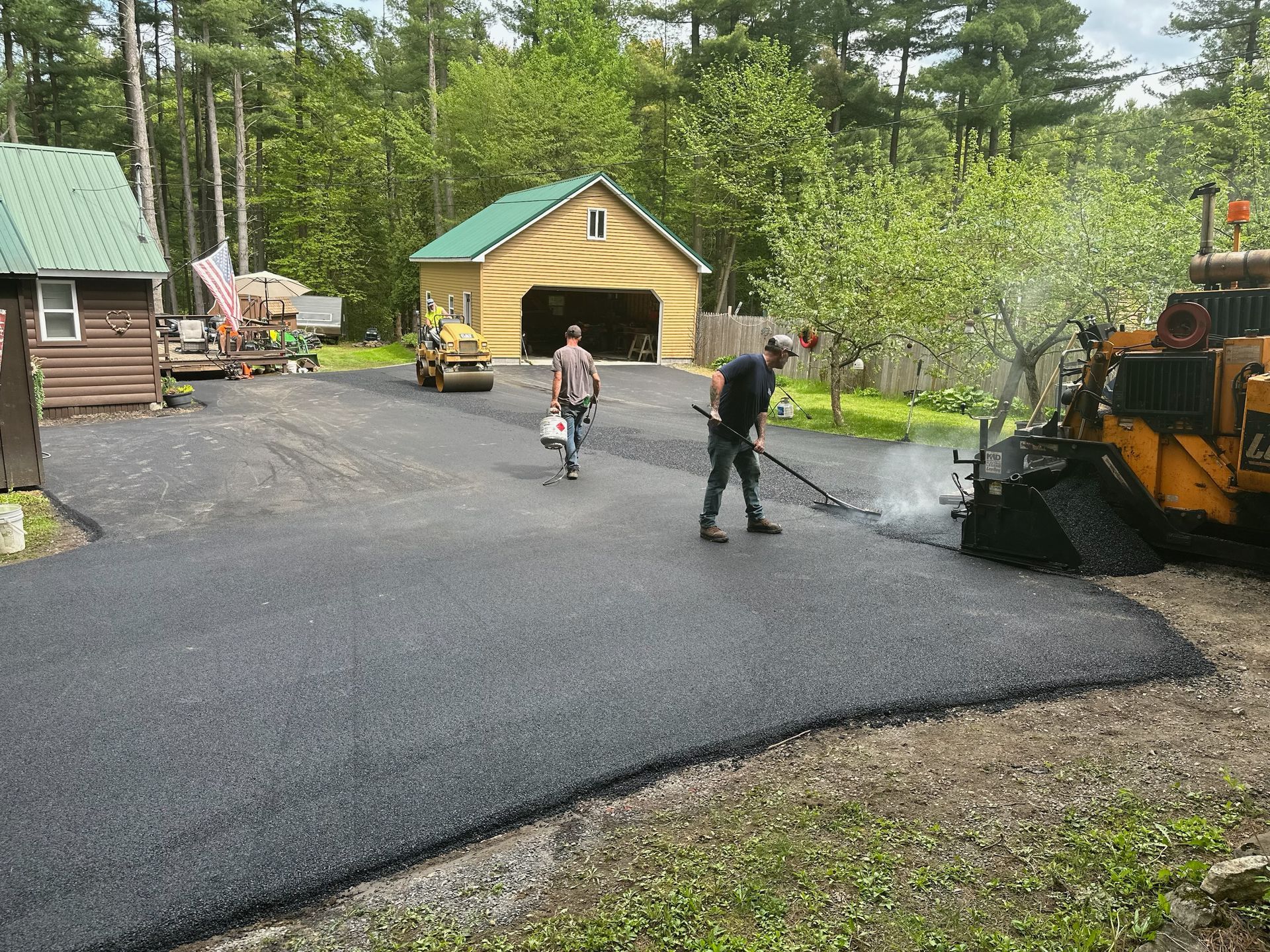 A group of people are working on a driveway in front of a garage.