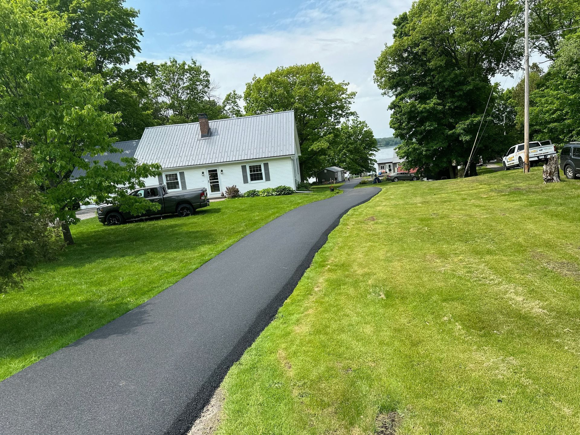 A house is sitting on top of a lush green hill next to a road.