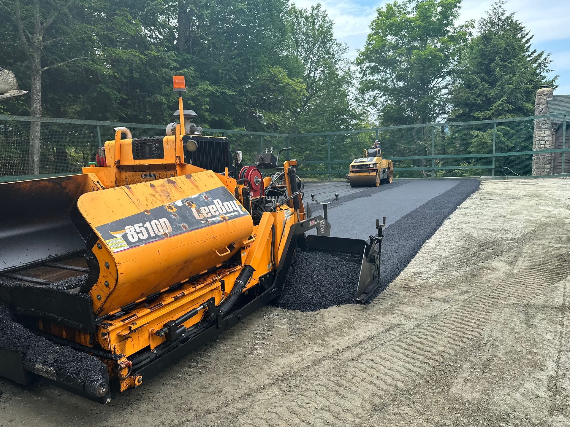 A yellow and black machine is laying asphalt on a road.