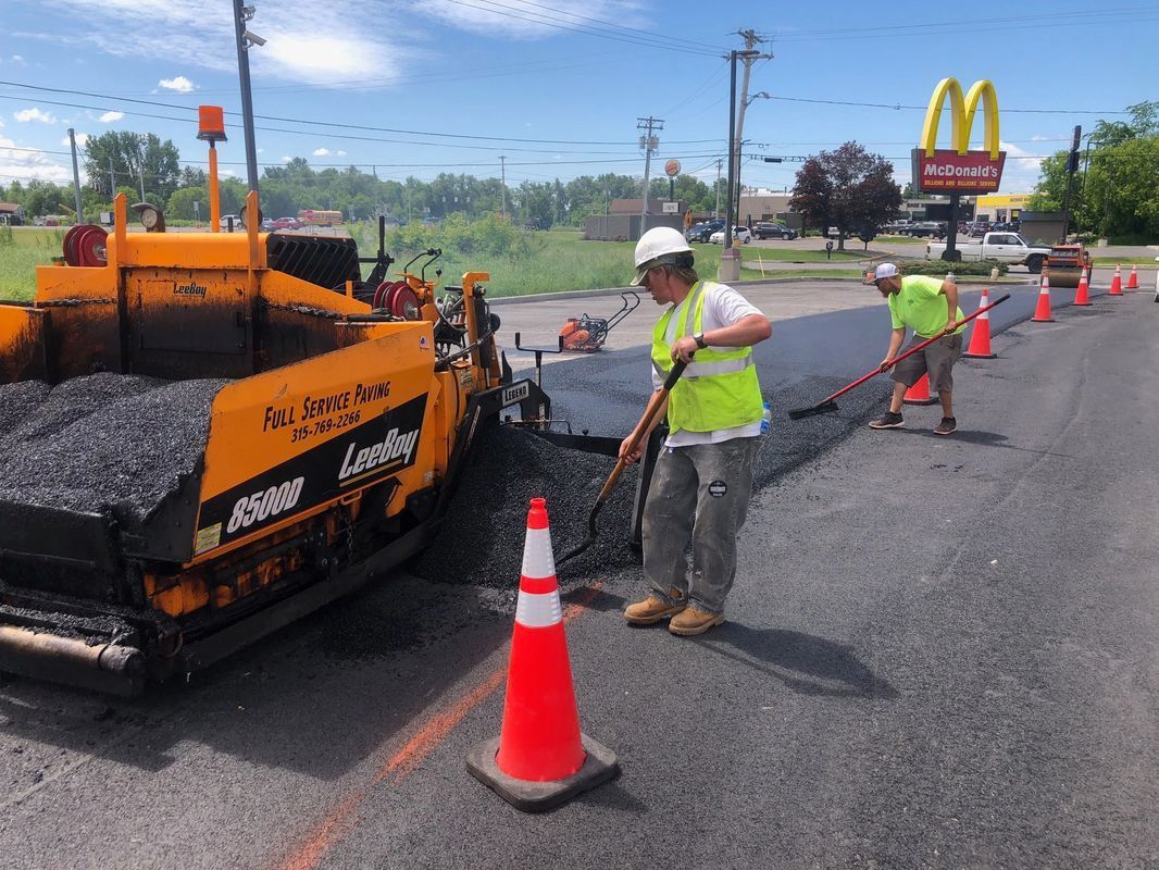 A group of construction workers are working on a road in front of a mcdonald 's.