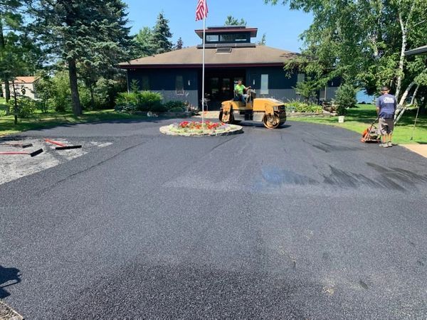 A man is working on a driveway in front of a house.
