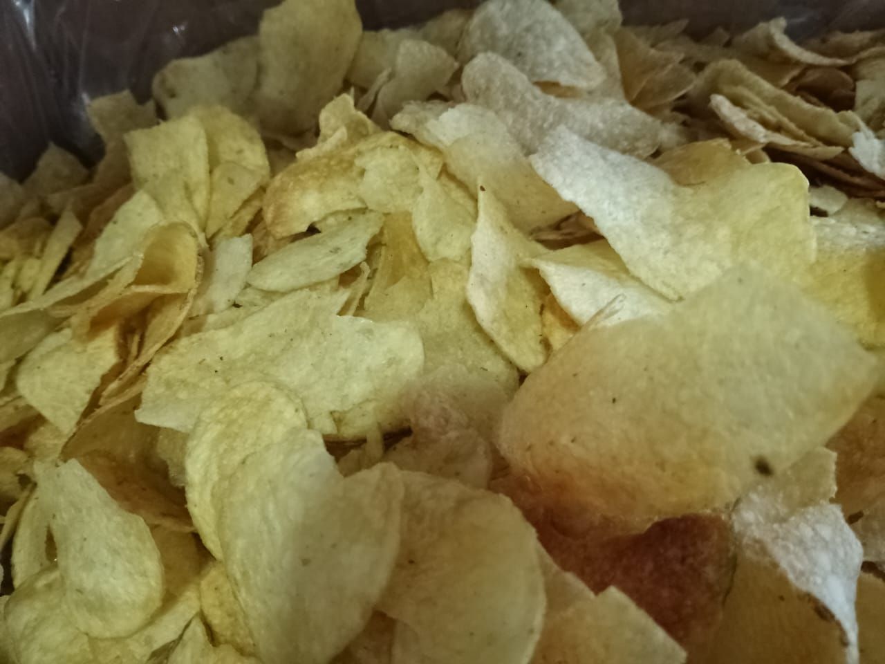 Primer plano de una pila de patatas fritas; finas, de color marrón dorado y ligeramente condimentadas.