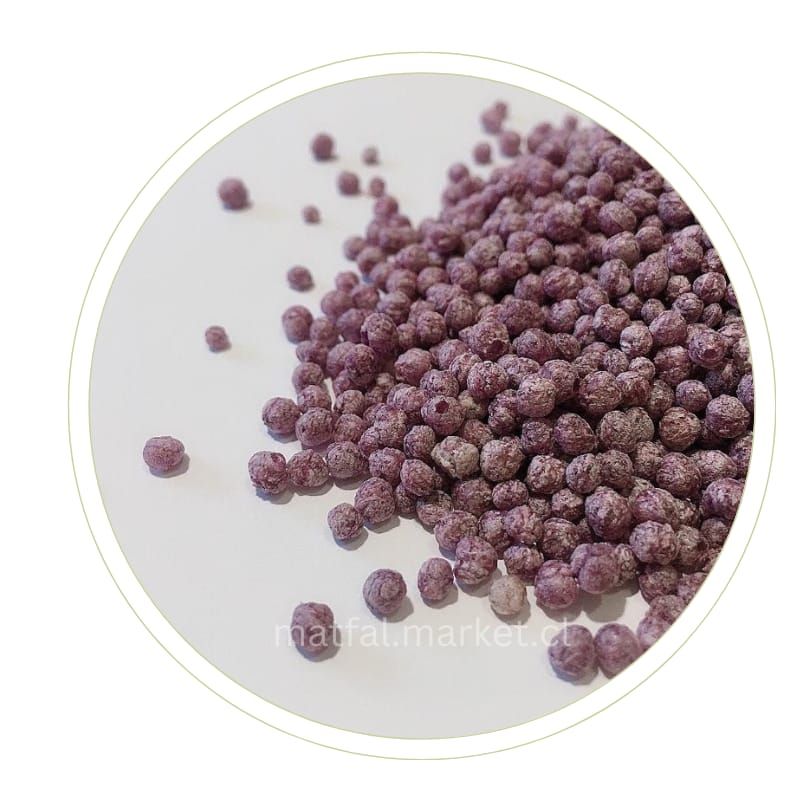 Montón de pequeños gránulos redondos de color púrpura sobre una superficie blanca.
