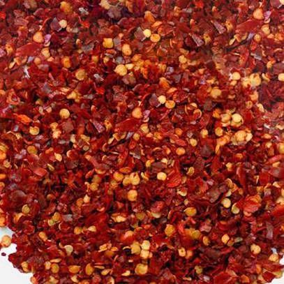 Hojuelas de chile rojo triturado, trozos pequeños de color marrón rojizo, un montón de especias.