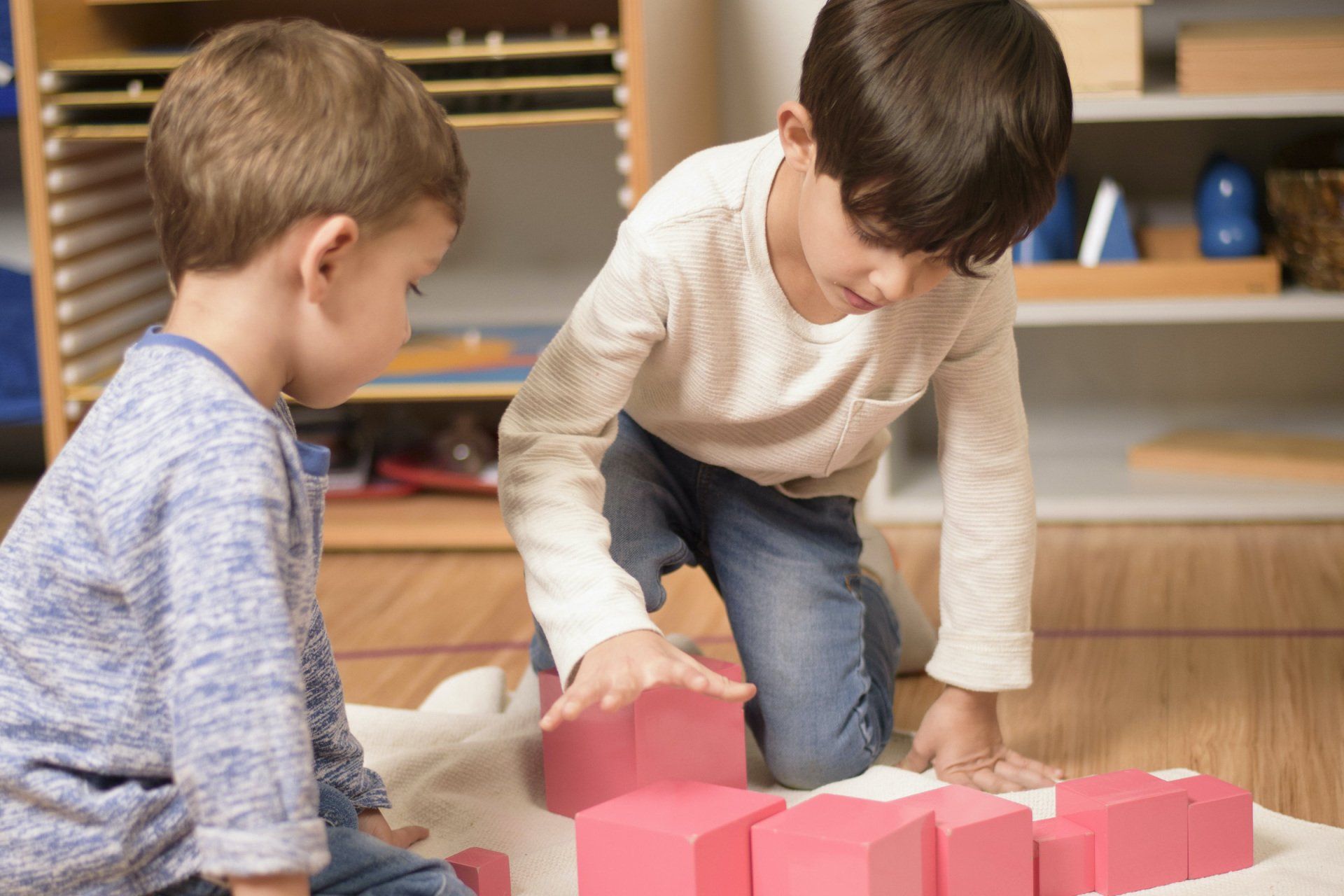 Montessori children working together with the pink tower