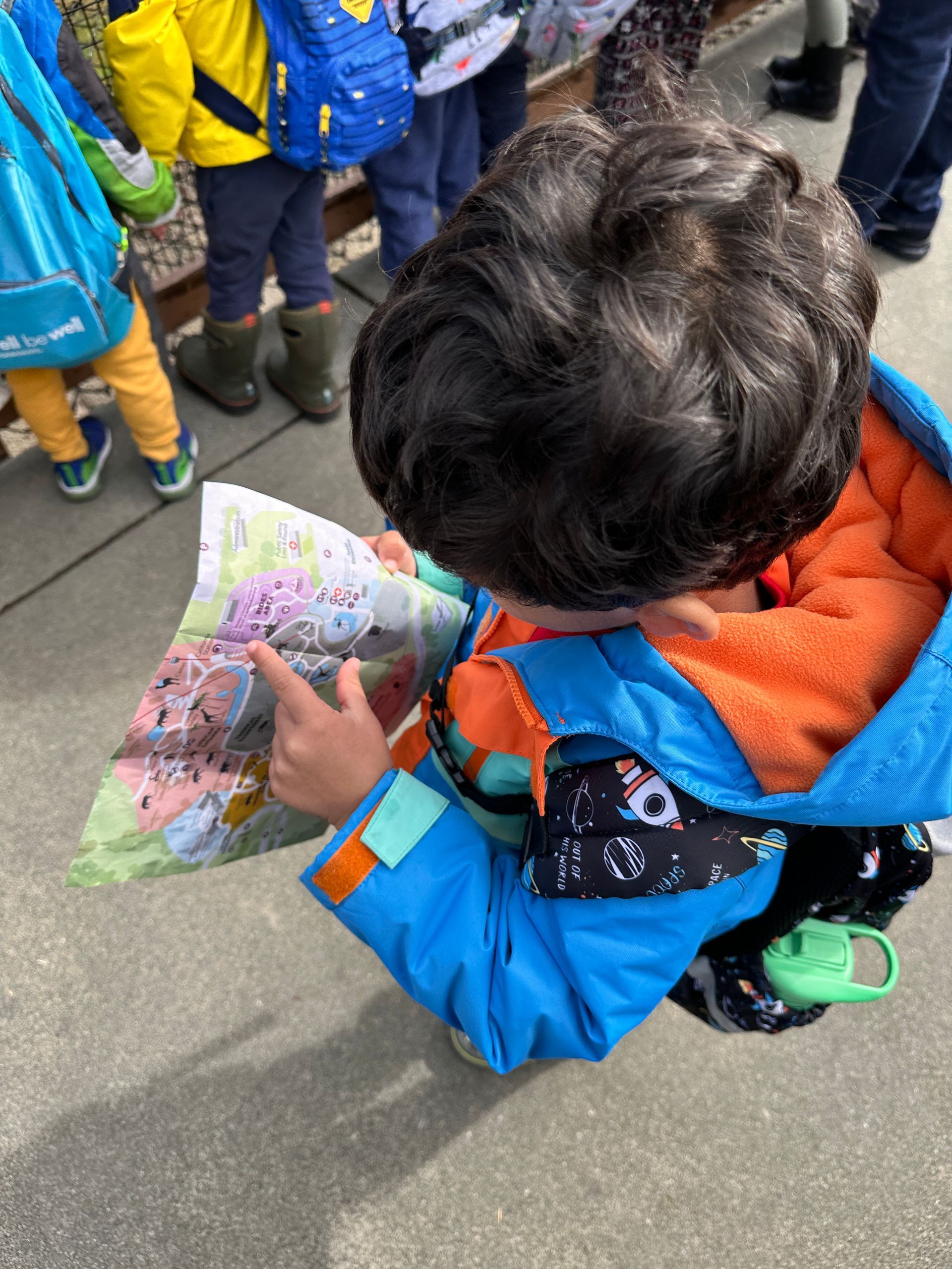 A Montessori child watching the tour map of the Oakland Zoo