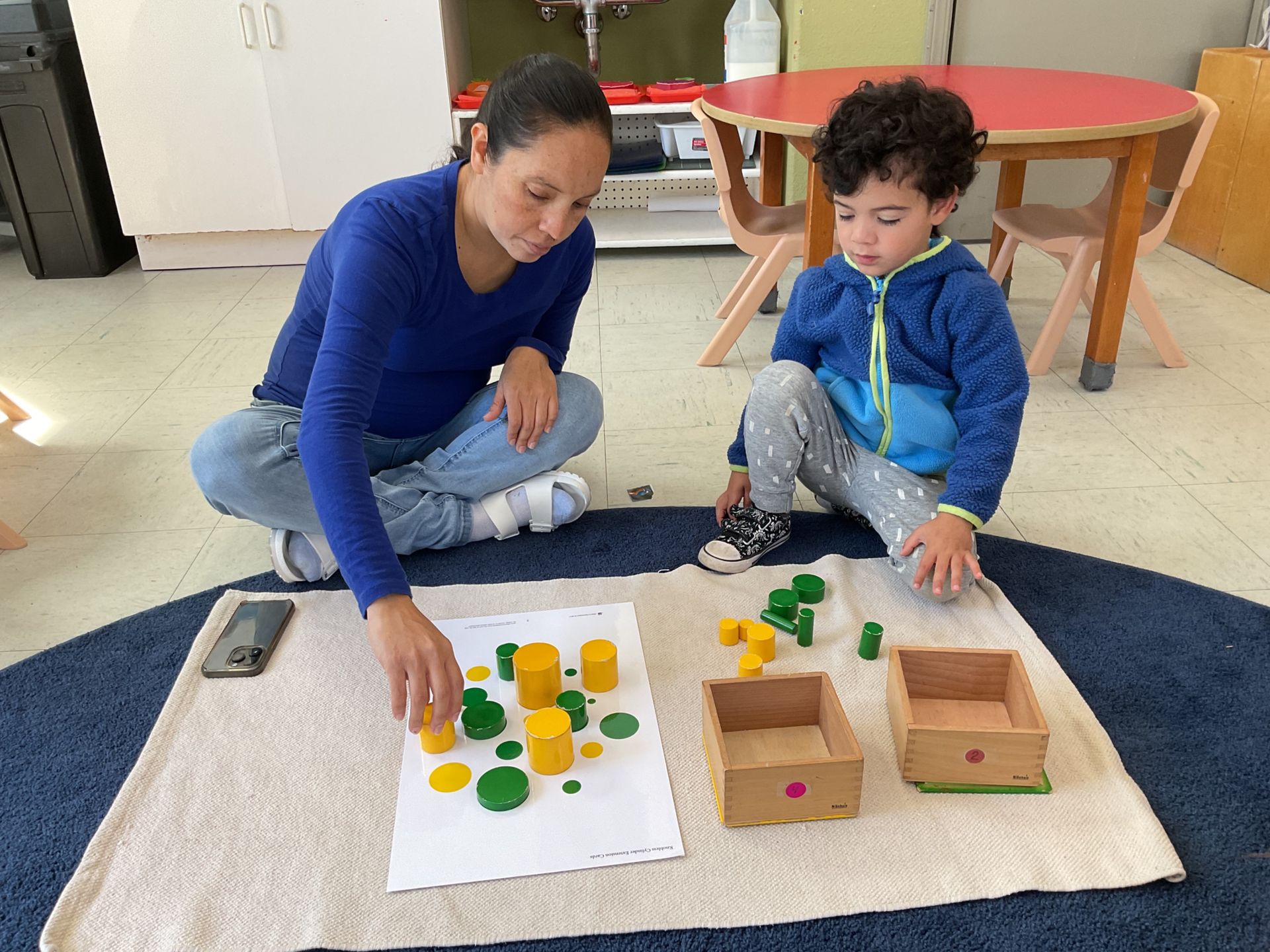 Montessori guide and child working with knobless cylinders