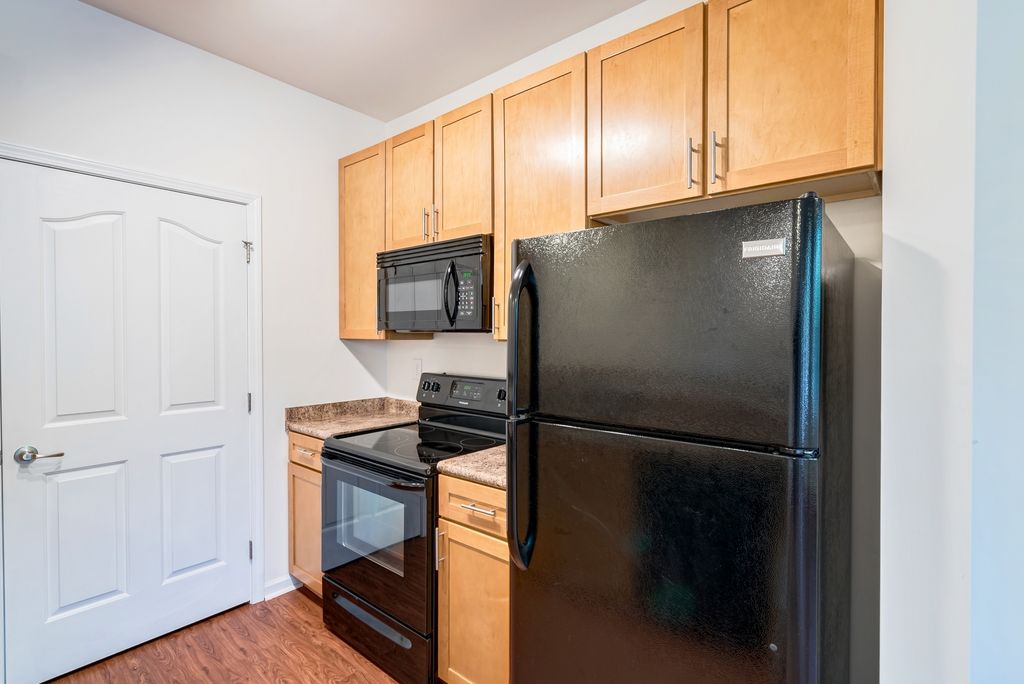 Interior view of a kitchen featuring wooden cabinets, an oven, and a black refrigerator