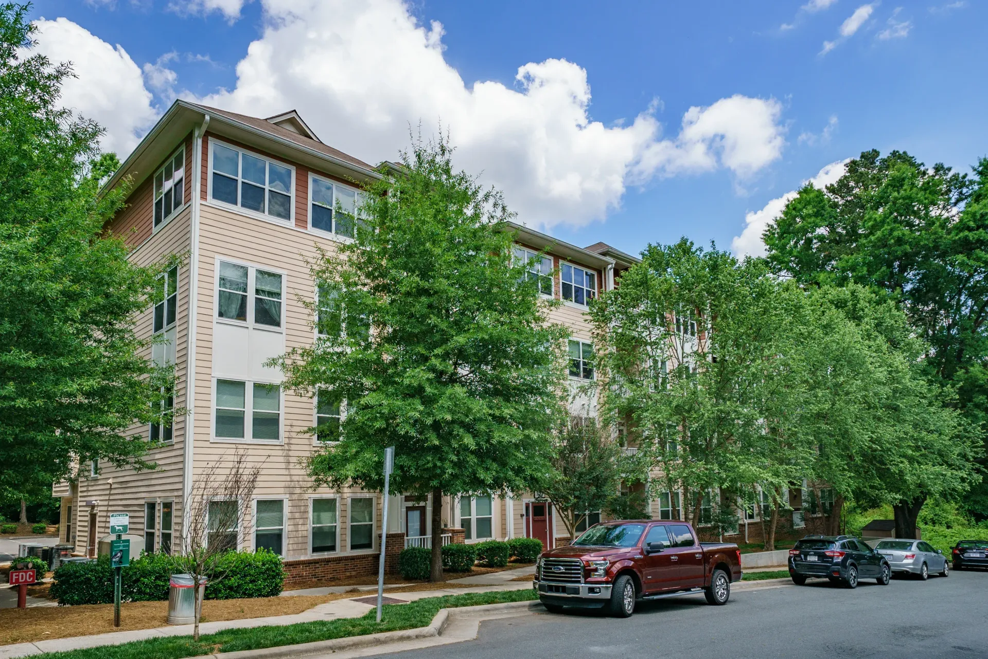 Exterior view of the property with trees and parked cars