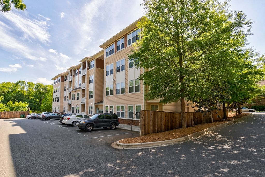 Exterior view of an apartment building with parking and trees