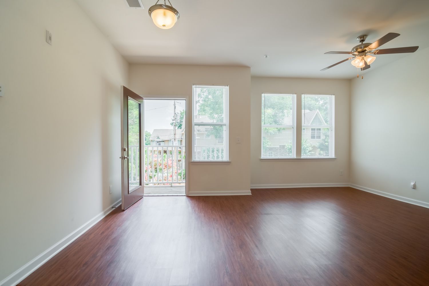 Interior view of a well-lit apartment living room with a door leading to a balcony.