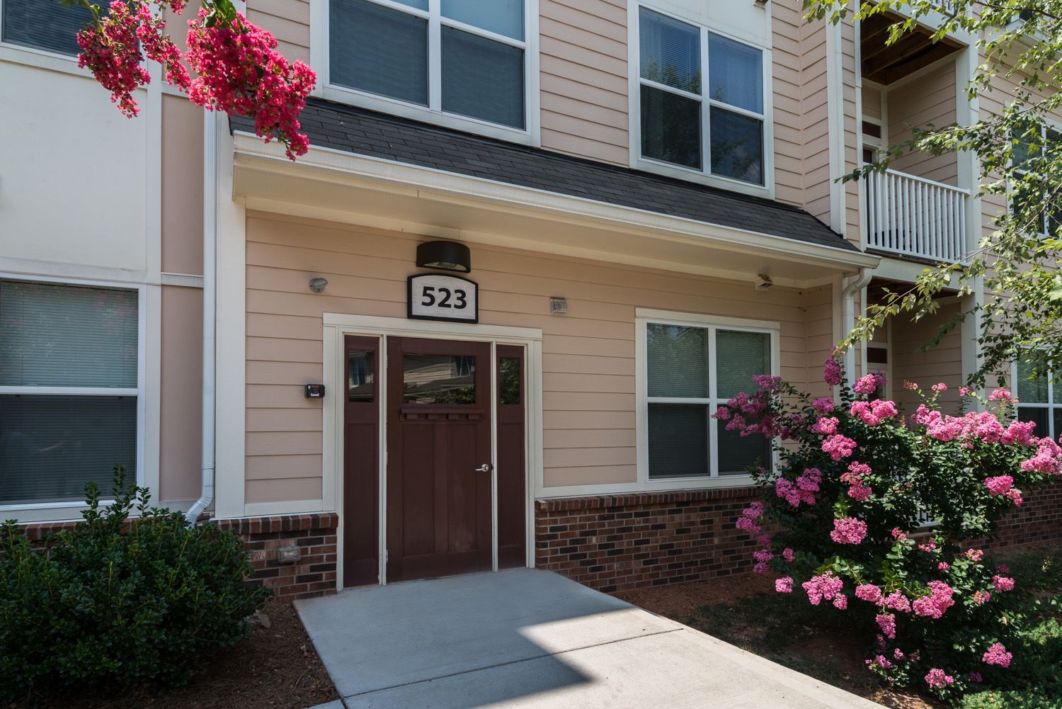 Front view of apartment door with number 523 surrounded by blooming flowers.