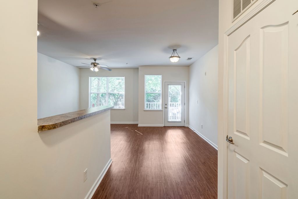 Interior view of an apartment living room with a wooden floor and large windows.
