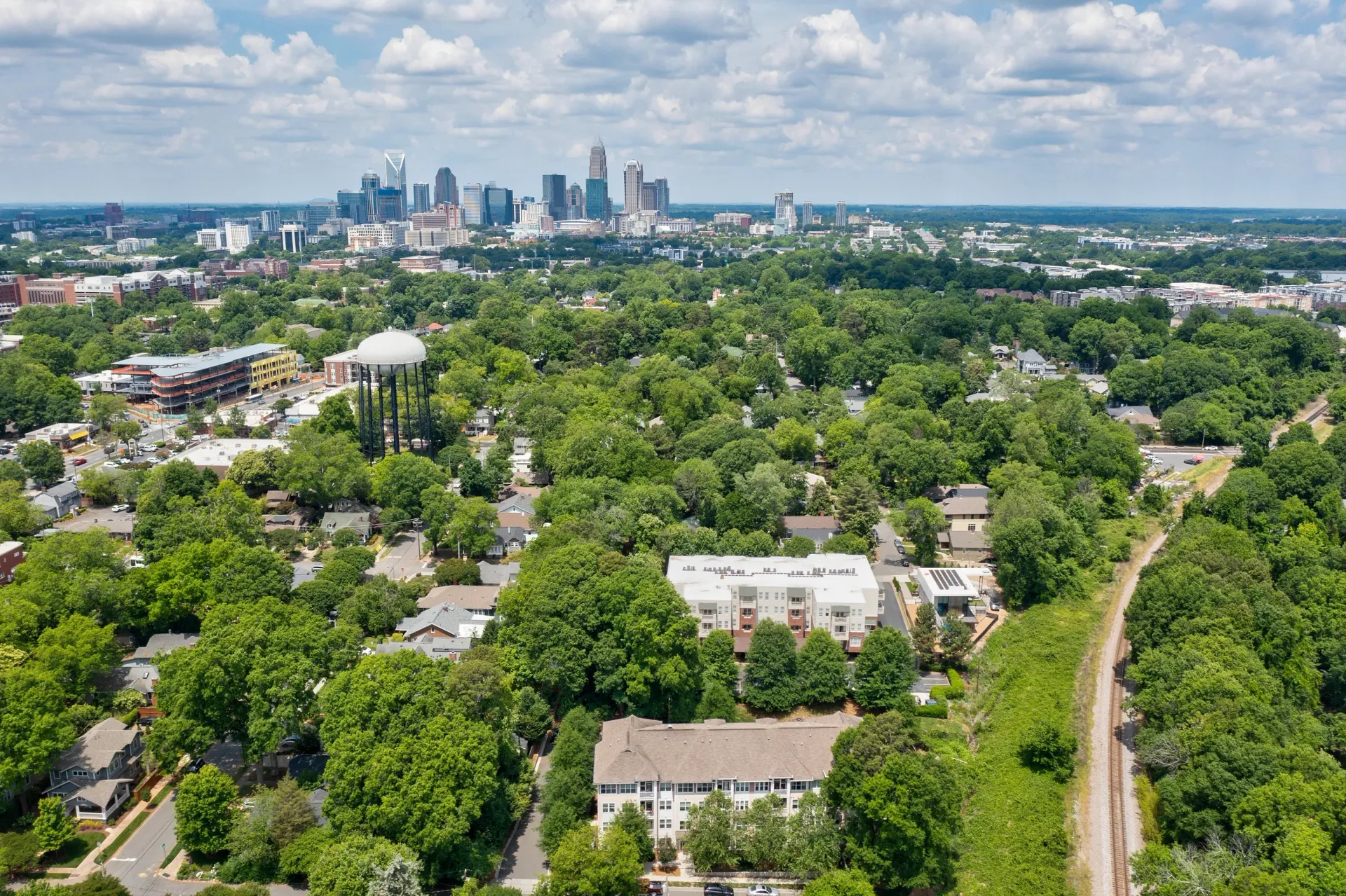 Aerial view of a green neighborhood with buildings and a city skyline in the background.