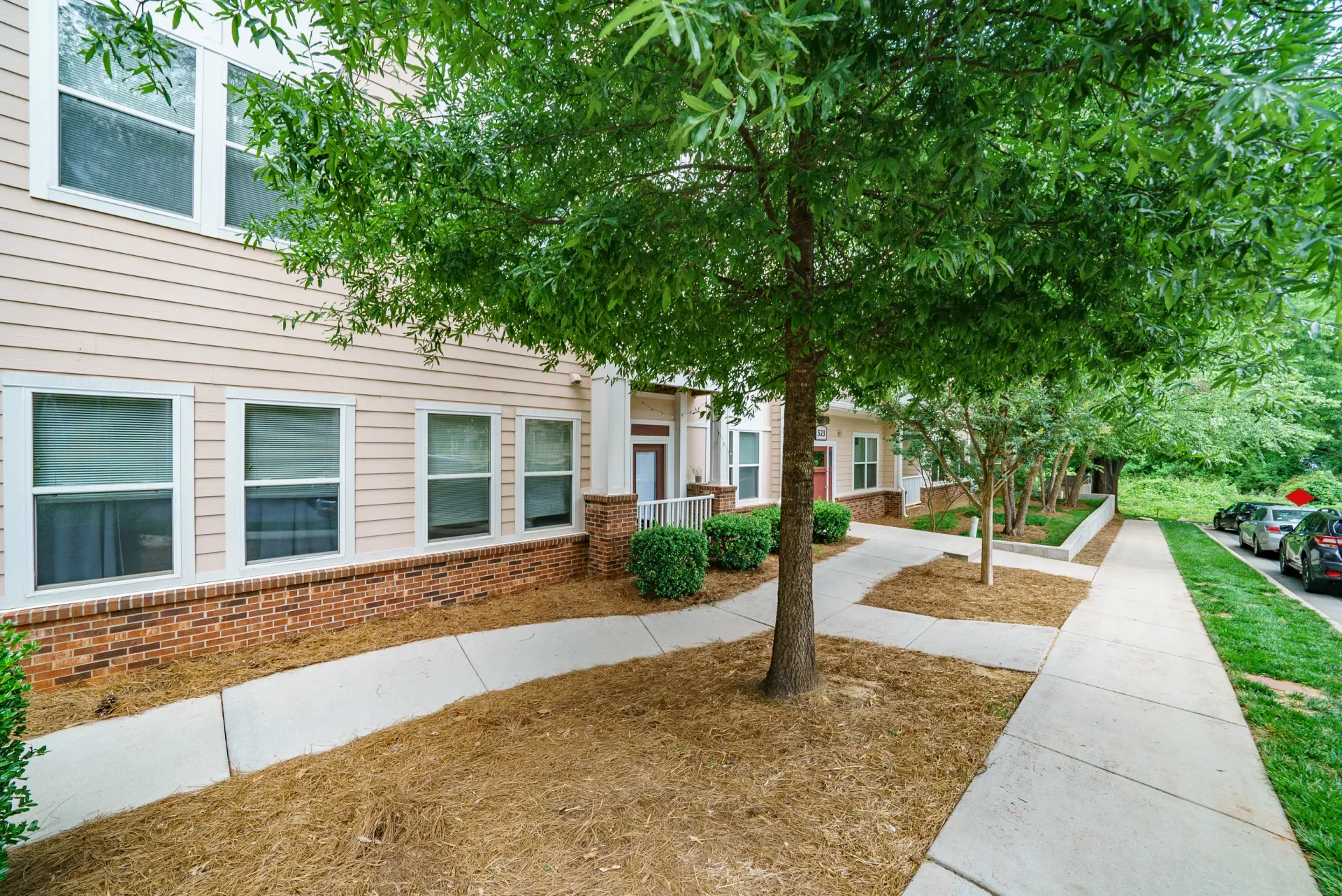 Exterior view of a property with landscaping, pathways, and trees
