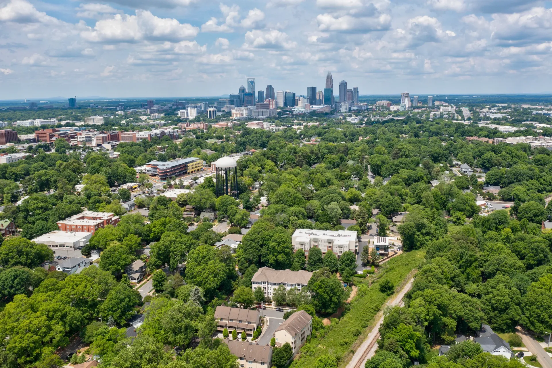 Aerial view of a green neighborhood with city skyline in the background
