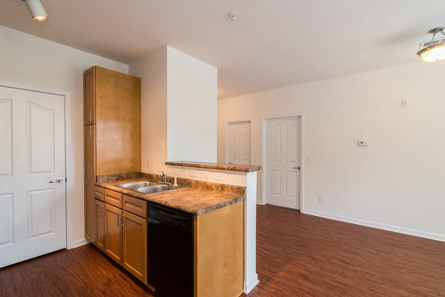 Interior view of a modern kitchen with brown cabinetry and dishwasher.