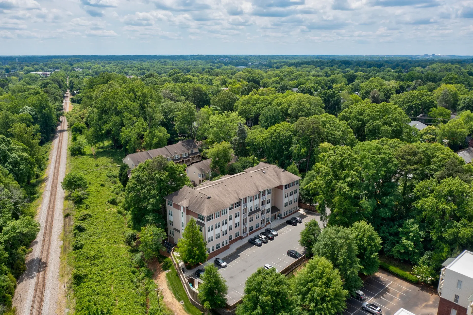 Aerial view of an apartment building surrounded by lush trees and greenery.