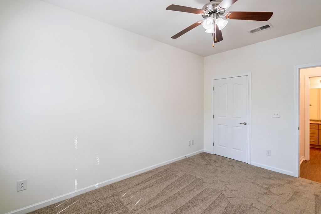Empty apartment room with a ceiling fan and carpeted floor