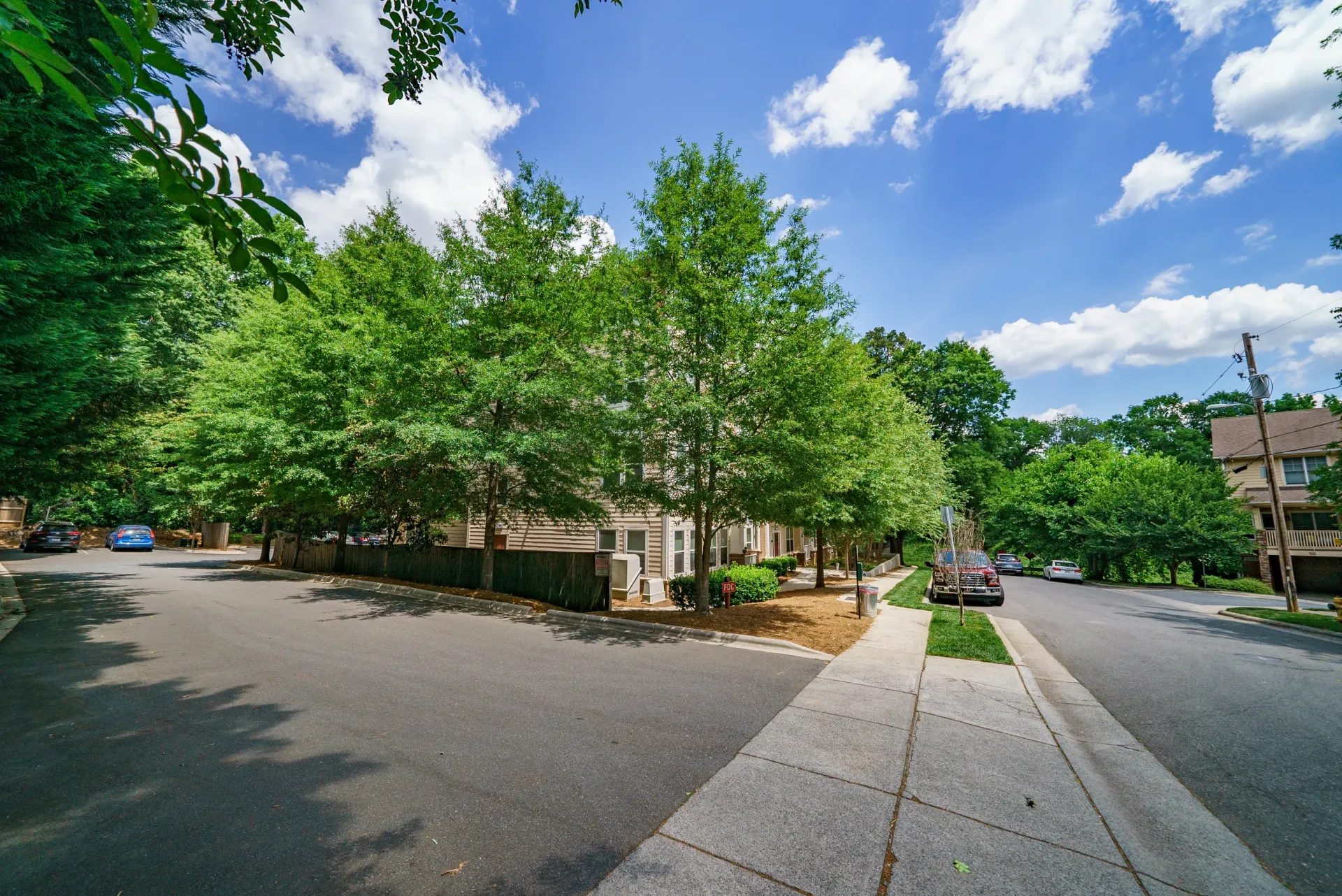 Exterior view of the property with trees and nearby parking.