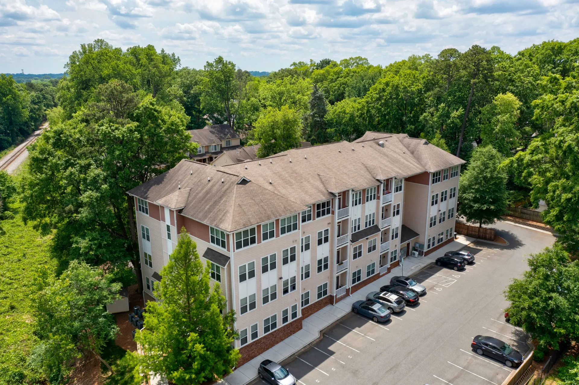 Aerial view of an apartment building surrounded by greenery and parking spaces.