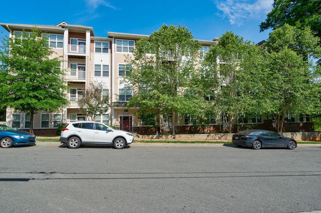 Exterior view of an apartment building surrounded by trees and parked cars