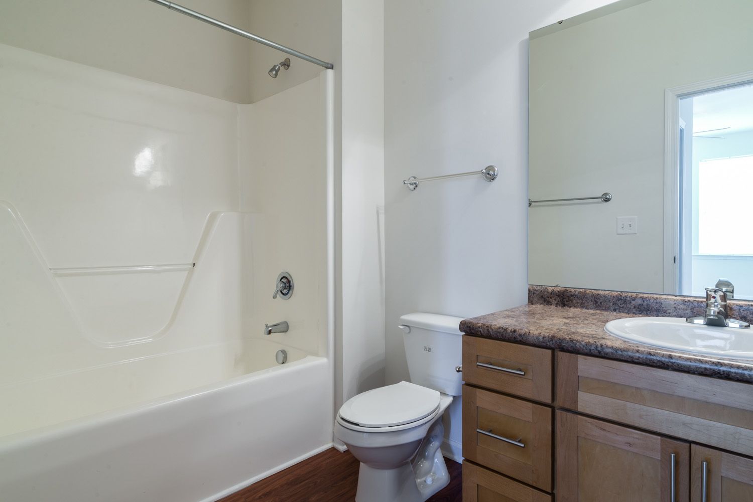 View of a clean and modern bathroom with a shower, toilet, and sink.