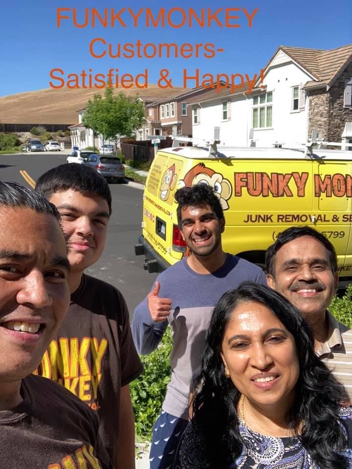 Five smiling people in front of a Funky Monkey junk removal van. One person gives a thumbs-up.
