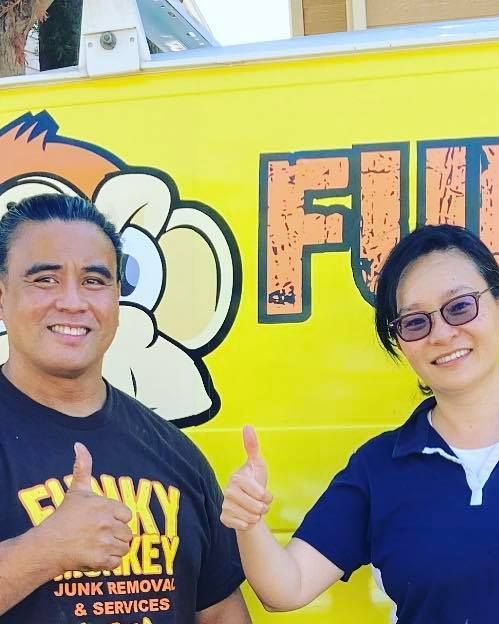 Two people giving thumbs up in front of a yellow truck with a monkey logo.