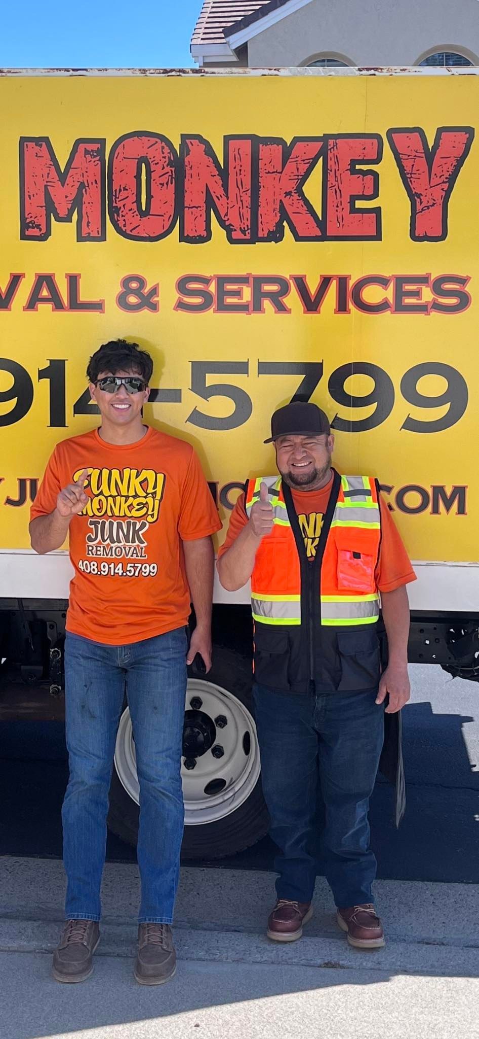 Two men stand in front of a yellow 