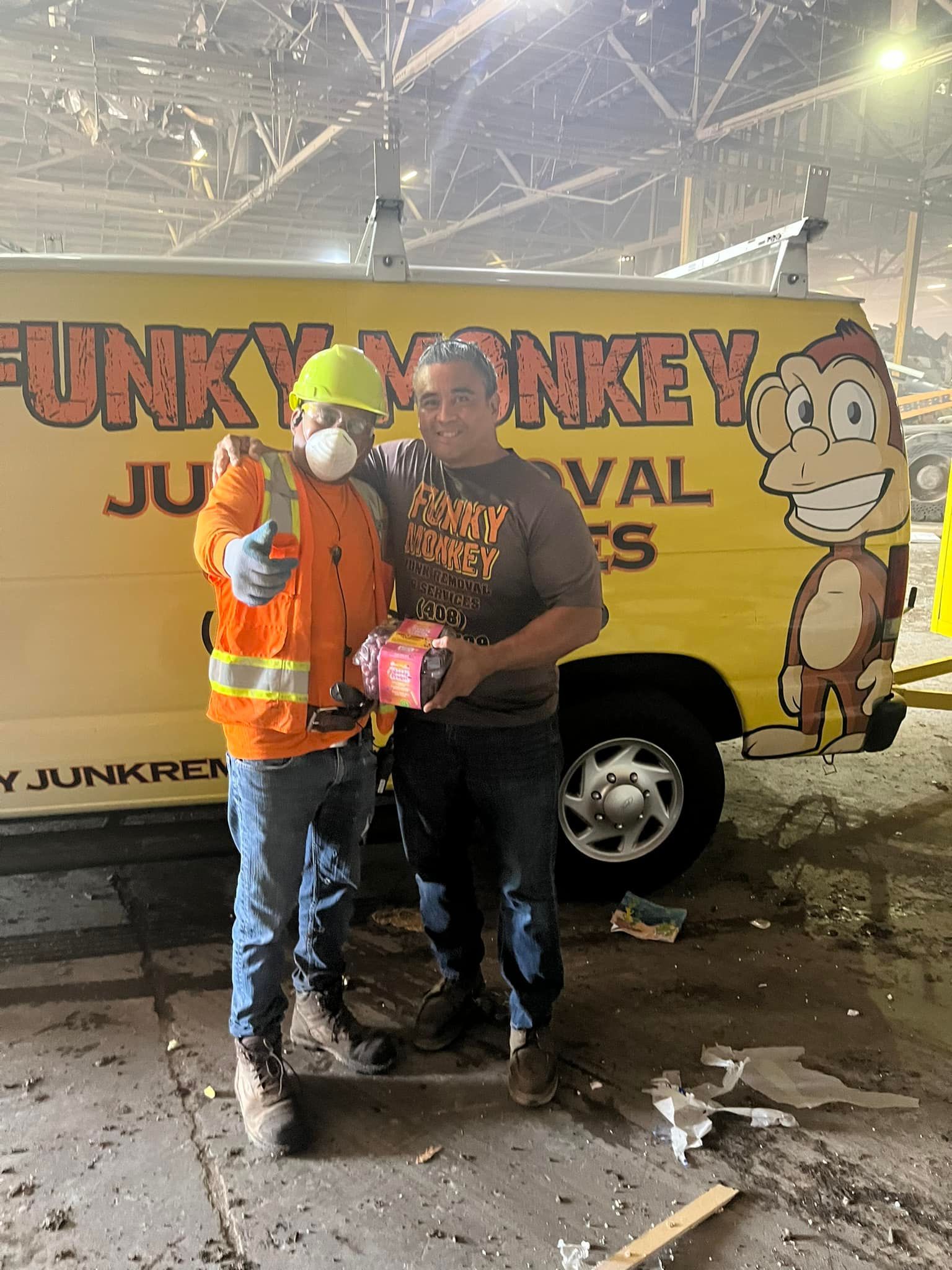 Two men stand in front of a yellow van, 