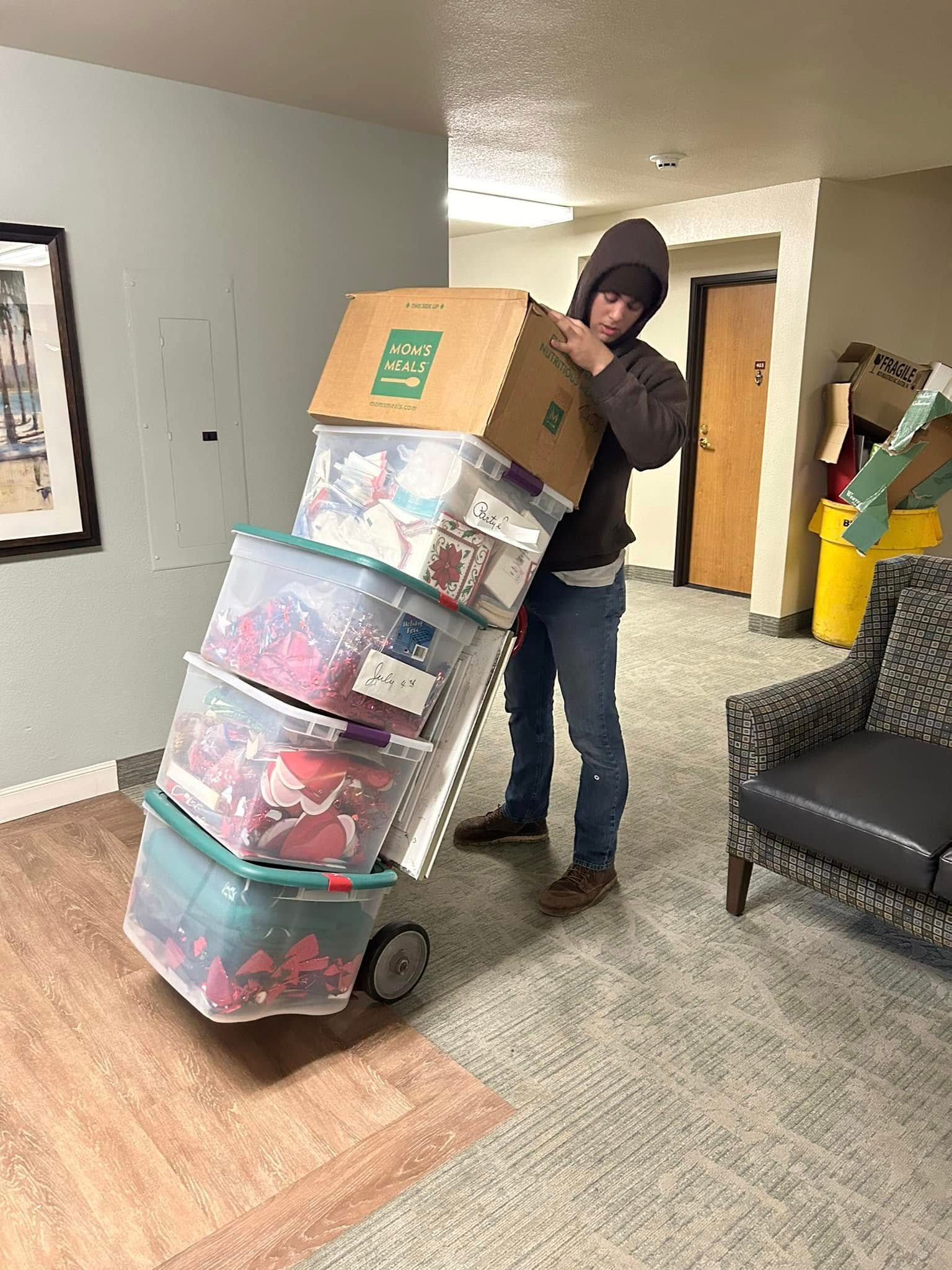 Person pushing a cart loaded with boxes and containers inside a building.