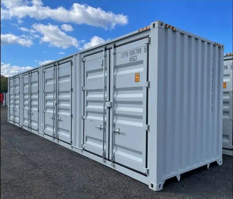 A row of shipping containers are lined up in a parking lot.