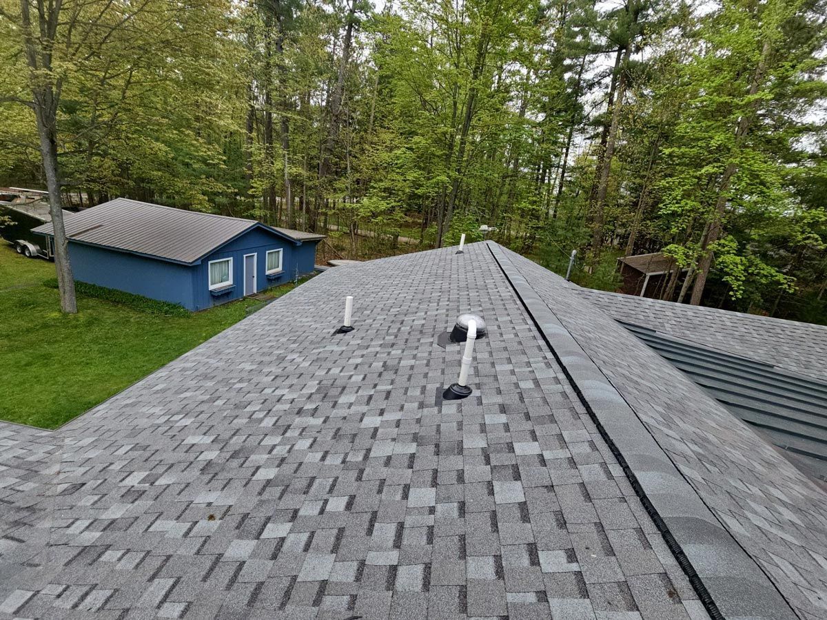 Roscommon, Michigan roofing project featuring Atlas shingles with a standing seam metal section on the low slope, installed by expert Northern Michigan roofers.